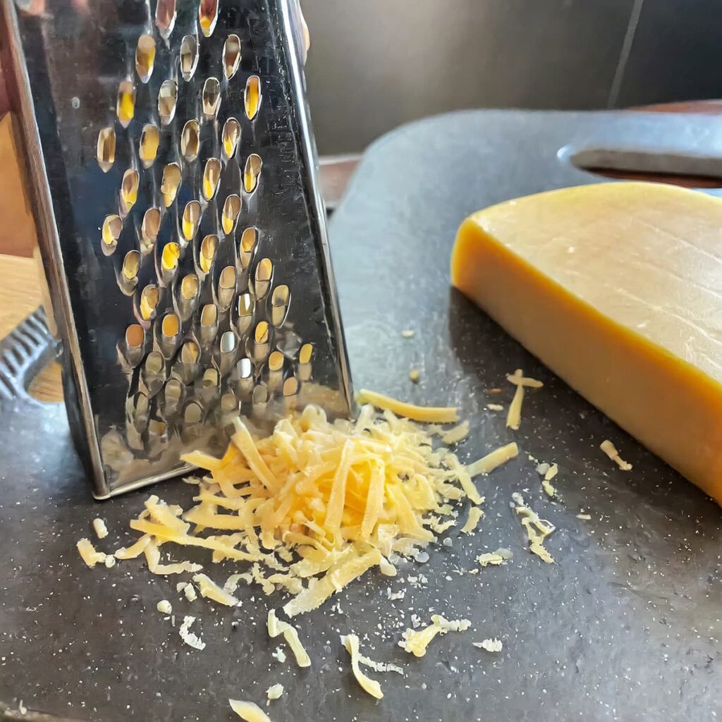 Rasp een blok kaas op een kaasrasp