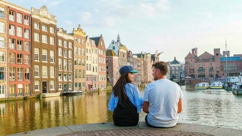 Romantische uitjes Amsterdam-damrak-sunset-happy-couple-man-woman-summer-evening-amsterdam-canals