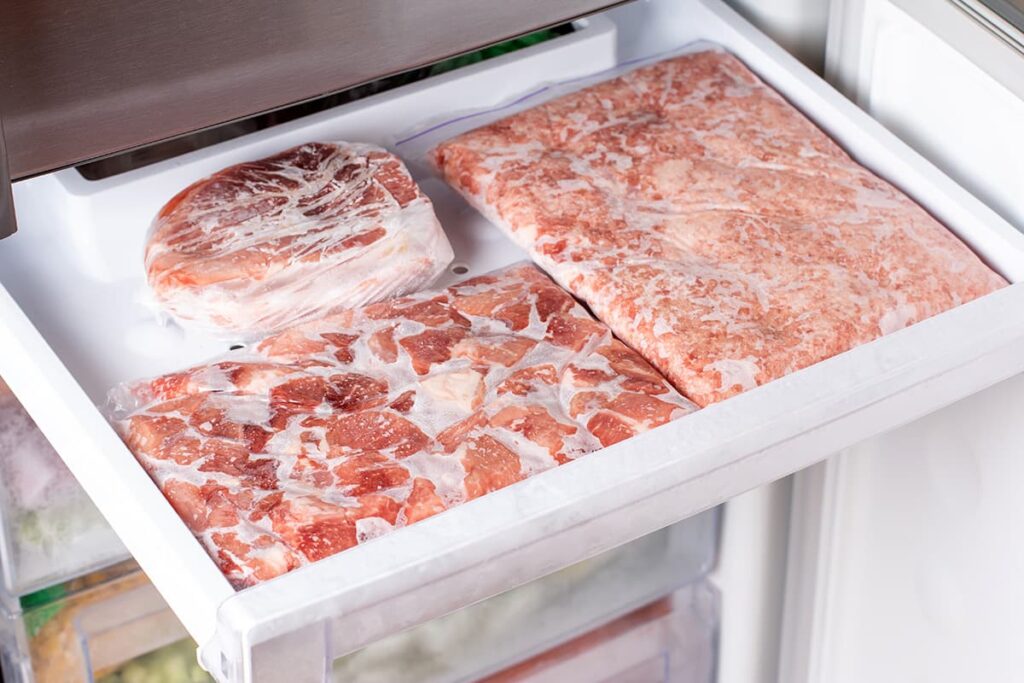 Bevroren vlees in plastic verpakking in de vriezer. Diepvries voedsel